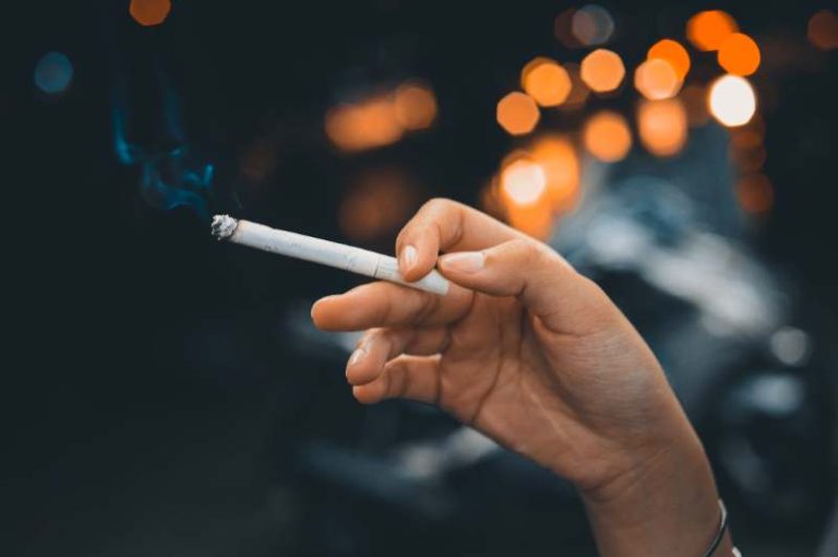 A person holding a cannabis joint with a Lasik eye surgery pamphlet in the background.