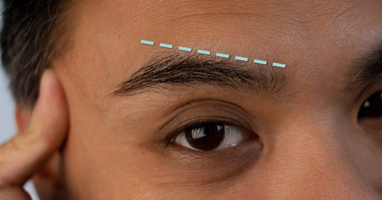 Person examining their eyebrows in the mirror after LASIK surgery.