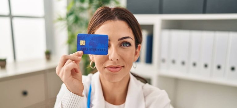 A person holding a credit card next to a calculator and a LASIK surgery brochure, considering payment options for the procedure.